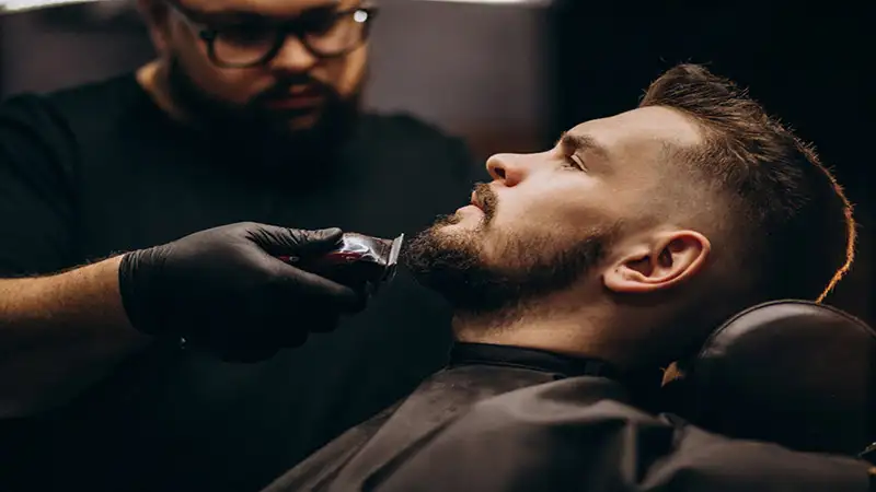 Foto de um barbeiro fazendo a barba de um homem