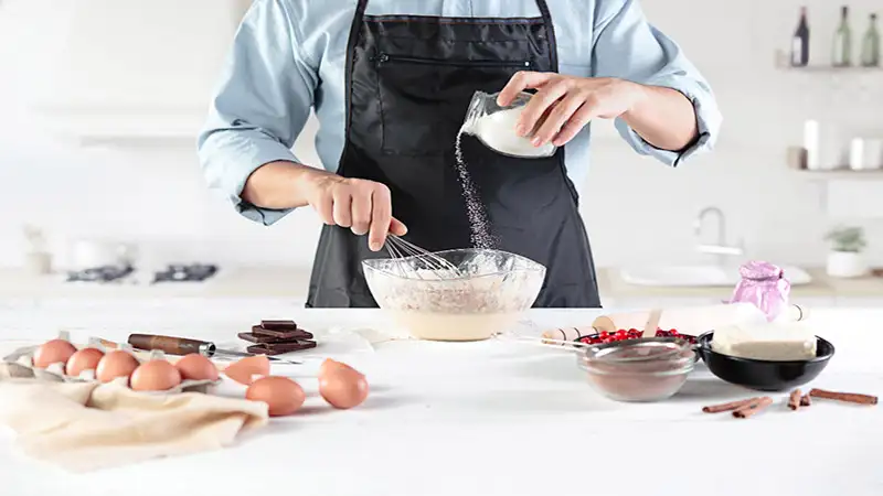 Foto de uma mulher preparando um bolo, derramando leite em um tijela