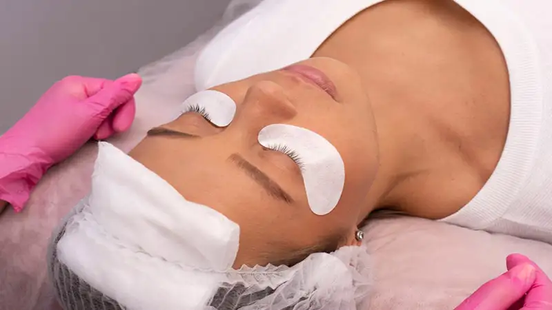 Foto de uma mulher deitada fazendo alongamento de cílios