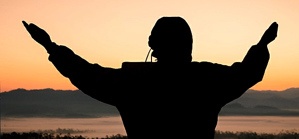 Silhueta de uma mulher lendo um livro no por do sol