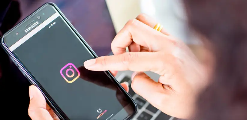 Frases para bio do Instagram Foto de uma pessoa segurando um celular enquanto navega no Instagram