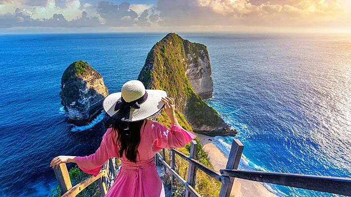 Foto de una mujer caminando en la playa de kelingking en la isla de nusa penida en bali, indonesia