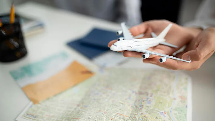 Manos sosteniendo un pequeño avión y un mapa en el fondo