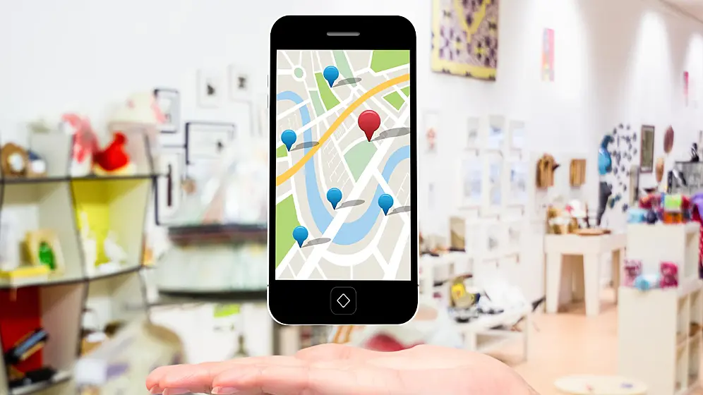Foto de una tienda de fondo y superpuesta, la imagen de un teléfono móvil con visualización de Google Maps