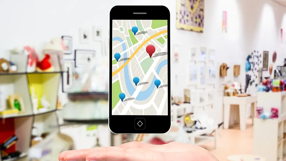 Foto de un mobile con imagen de Google Maps y, por detrás, una tienda online