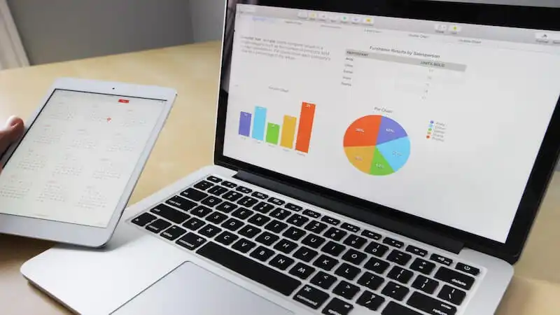 The image shows a laptop screen with graphichs on it, and on the left side there is a tablet. 