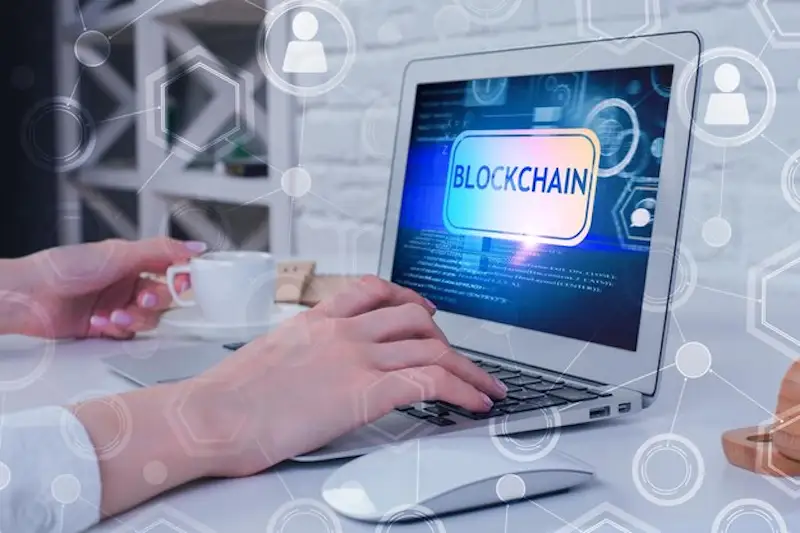 How IoT and and blockchaing are changing billing - secure billing The iamge shows someone using a laptop, in the screen it's written "blockchain".