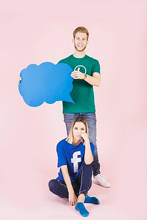 The image shows a man holding a speech bubble, and a girl sitting in front of him with a Facebook t-shirt.