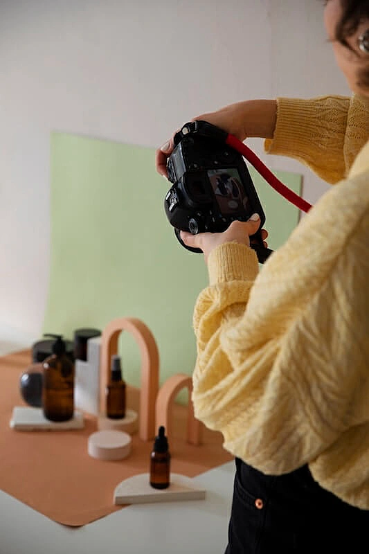 The image shows a woman photographing a set of products.