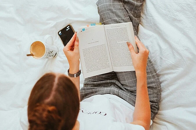 The image shows a woman reading a book