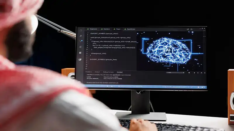 Foto de uma pessoa usando um computador e códigos na tela