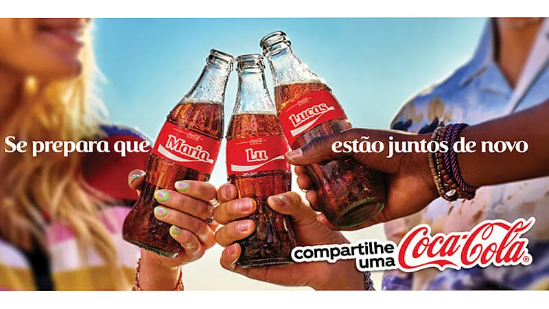 imagem promocional da campanha "compartilhe uma coca-cola" onde três pessoas estão brindando com garrafas de vidro com os nomes Maria, Lu e Lucas no rótulo