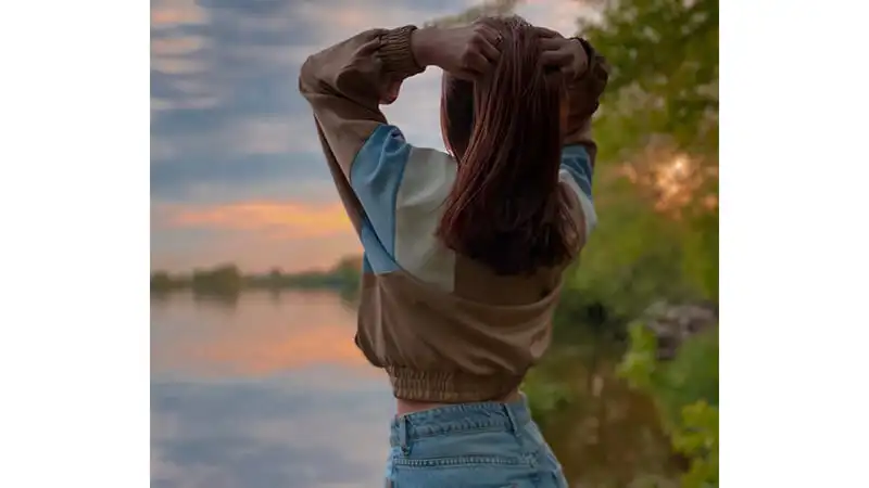 Foto de uma menina de costas segurando o cabelo
