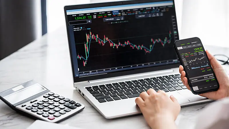 Foto de pessoas usando notebooks e vários números e gráficos na tela