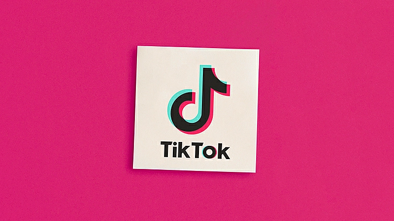 Ilustração de uma pessoa sentada e um celular com a logo do TikTok