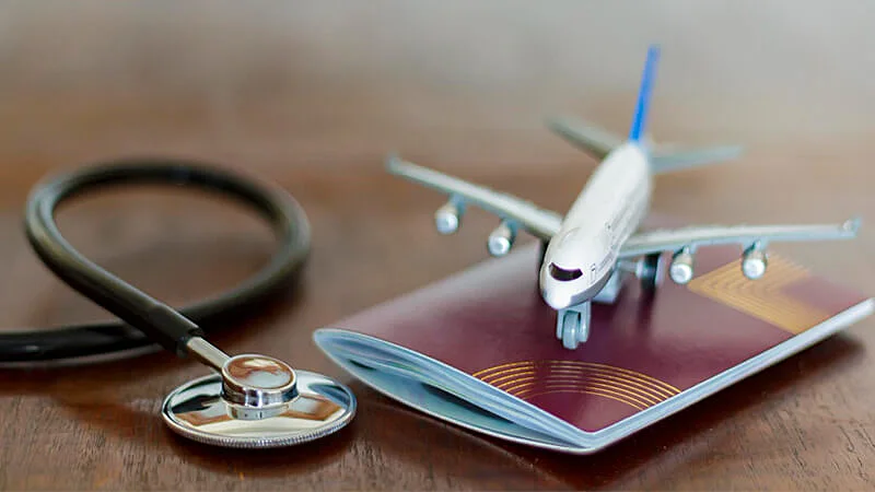 foto de uma mala, um passaporte e um estetoscópio