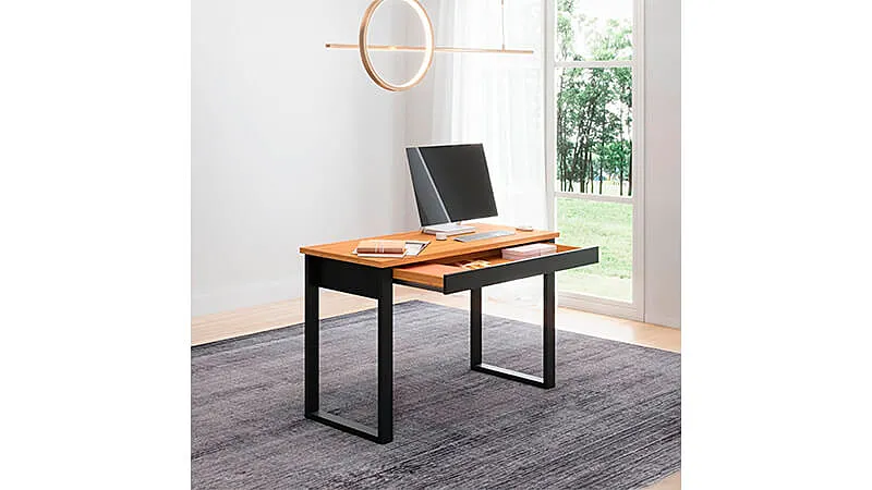 imagem de uma mesa para escritório com gaveta no estilo industrial em uma sala com chão de madeira, tapete cinza e uma janela ao fundo