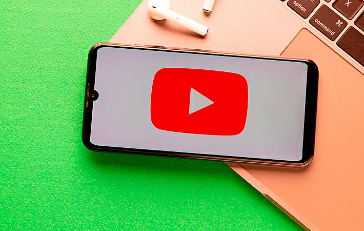 Foto de uma mão segurando um papel com a logo do YouTube