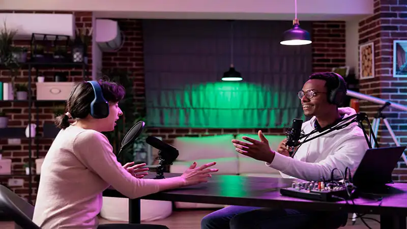 nome para podcast Foto de duas pessoas sentadas conversando em um podcast