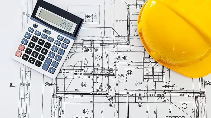 Foto de uma pessoa analisando projetos em cima de uma mesa