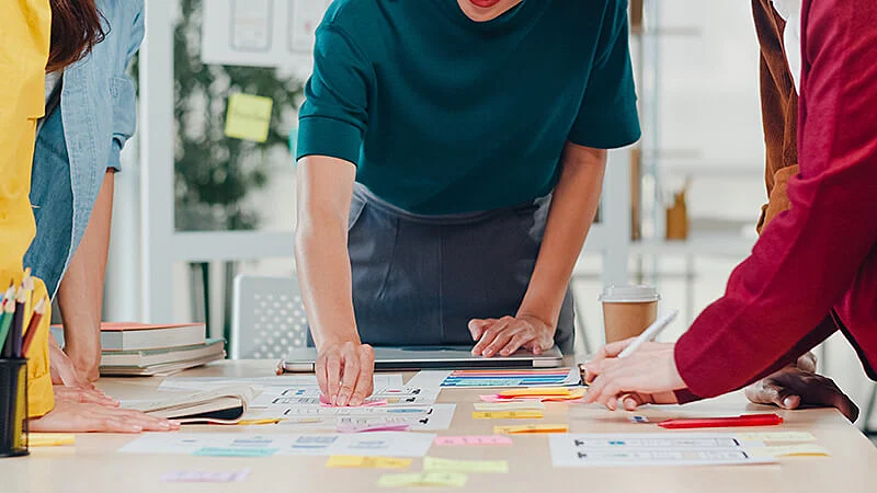 Foto de pessoas trabalhando em uma mesa cheia de papeis