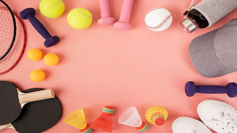 foto de vários equipamentos esportivos, como bolas, peso de academia, tenis e boné