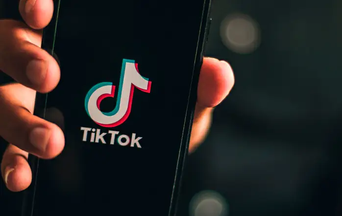 Nomes para TikTok Foto de uma pessoa segurando um celular com a logo do TikTok