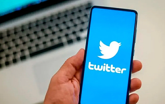 Foto de uma pessoa segurando um celular com a logo do Twitter