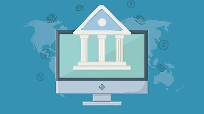 Tela de um computador com um banco à mostra, atrás um mapa mundi com moedas