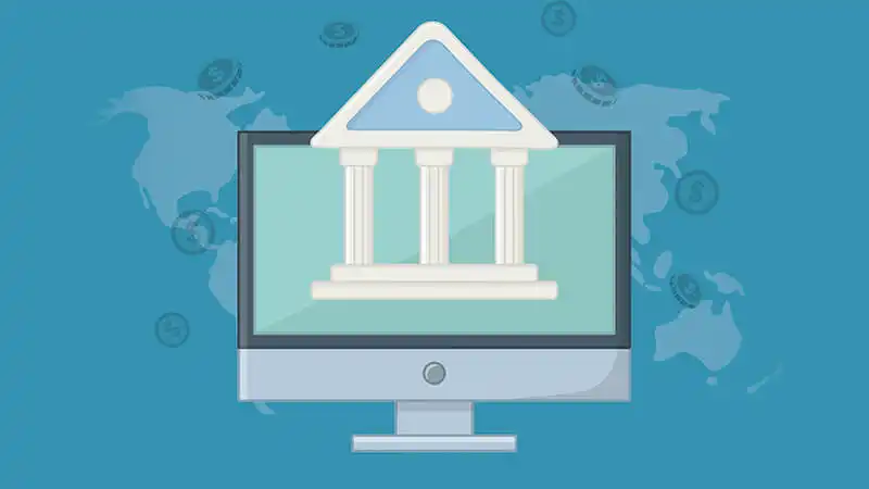 Tela de um computador com um banco à mostra, atrás um mapa mundi com moedas