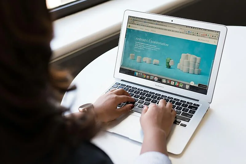 The image shows a woman using a laptop.