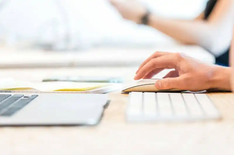 The image shows a person's hand in front of a computer screen
