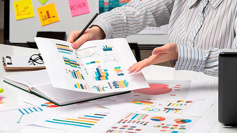 Homem analisando gráficos e mexendo em um notebook