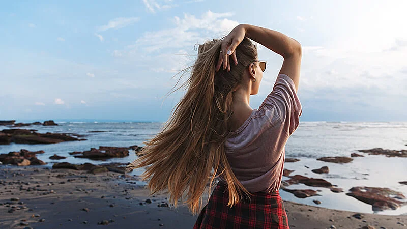 Foto de uma menina de costas segurando o cabelo