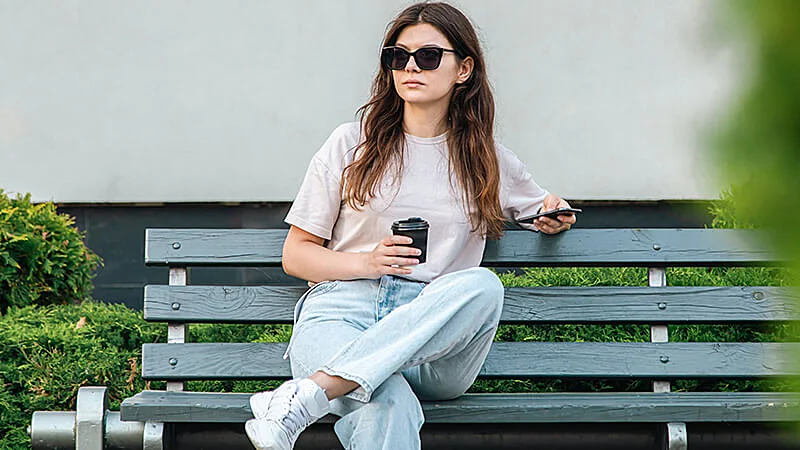 Foto de uma mulher sentada em um banco com as pernas cruzadas