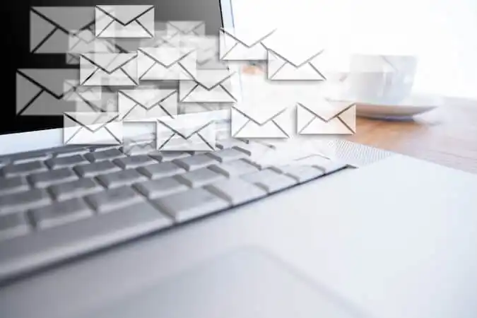 Laptop keyboard with multiple email message icons representing email marketing or high volume of digital communication.
