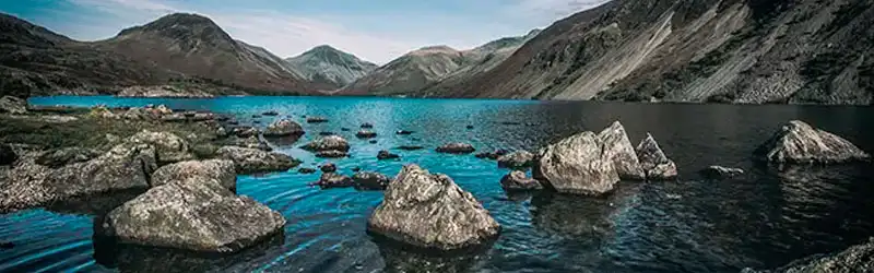 Paisagem com um lago, pedras e montanhas ao fundo