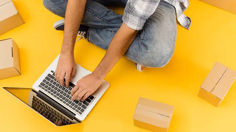 Foto de uma pessoa utilizando um notebook e embalagens