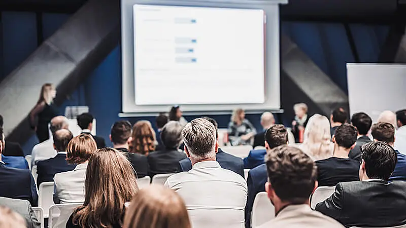 Foto de um homem em pé apresentando para outras pessoas sentadas