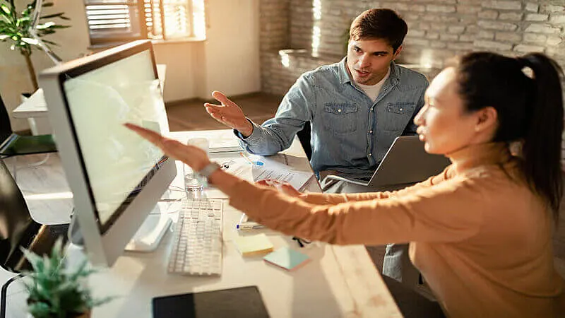Foto de duas pessoas analisando gráficos em um computador