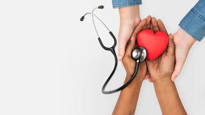Foto de manos sosteniendo un corazón rojo y un estetoscopio