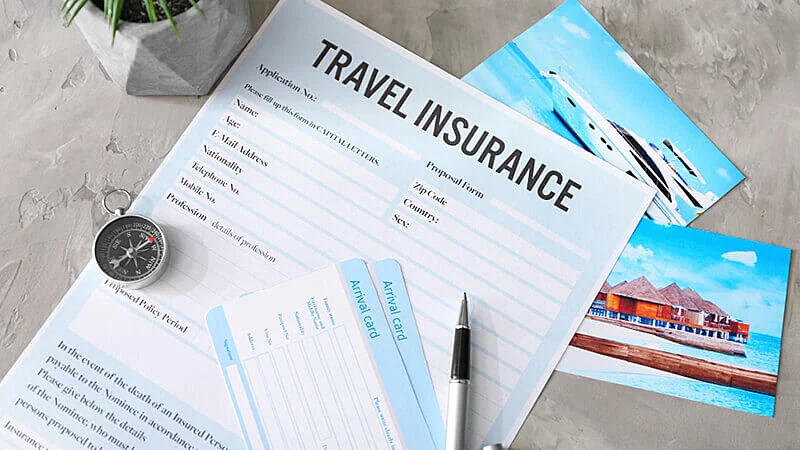 Foto de um documento de seguro viagem, dois passaportes e um avião em miniatura em cima de uma mesa