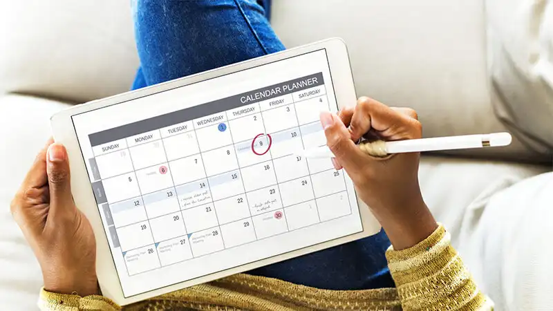 Sistema de agendamento online Foto de uma pessoa usando um tablet com calendário aberto