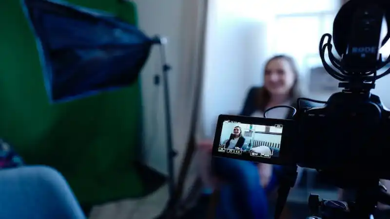 The imagem shows a woman been recorded by a camera.